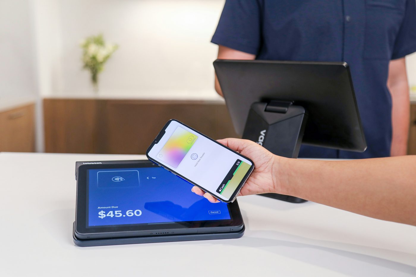 A business owner using a handheld POS device to ring up a customer